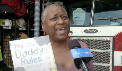 Hope Anita Smith at Fire Station holding her book My Daddy Rules the World