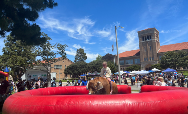 Kid riding a mechanical bull in front of ESHS at the hometown fair