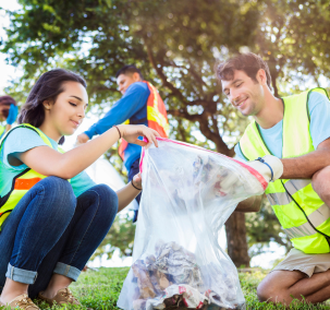 people in a park on a sunny day picking up trash