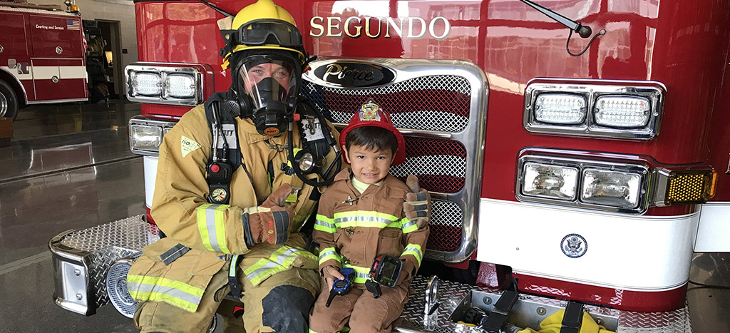 firefighter in turnout gear gives a station tour to a child